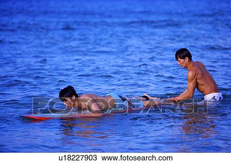 Man helping young man floating on the sea with the surfboard View Large Photo Image Stock Image - Man helping young man floating on the sea with the surfboard. Fotosearch