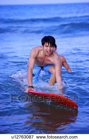 Man helping young man sufing on the sea View Large Photo Image Stock Photo - Man helping young man sufing on the sea. Fotosearch