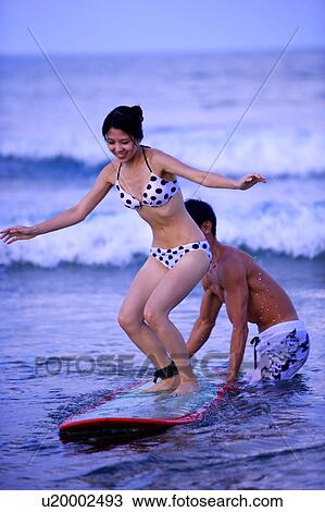 Man helping young woman standing on the surfboard View Large Photo Image Stock Image - Man helping young woman standing on the surfboard. Fotosearch