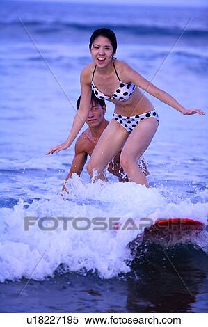 Man helping young woman surfing on the sea View Large Photo Image Stock Photography - Man helping young woman surfing on the sea. Fotosearch