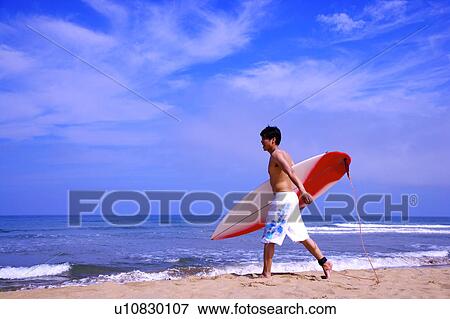 Man holding the surfboard and walking toward the sea View Large Photo Image Stock Photo - Man holding the surfboard and walking toward the sea. Fotosearch
