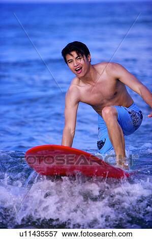 Stock Photo - Man surfing on the sea and smiling happily. Fotosearch