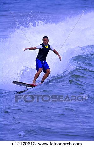 Stock Image - Man surfing on the sea with arms outstretched. Fotosearch