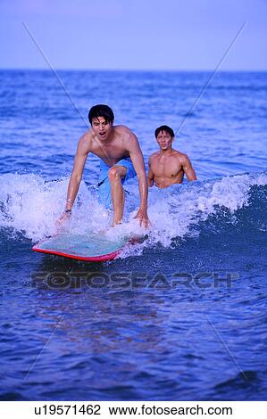 Man teaching young man surfing on the sea View Large Photo Image Stock Image - Man teaching young man surfing on the sea. Fotosearch