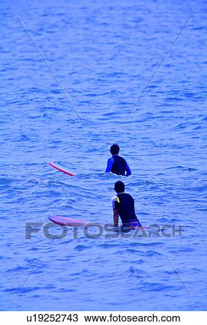 Two men standing in the sea and holding the surfboard View Large Photo Image Stock Image - Two men standing in the sea and holding the surfboard. Fotosearch