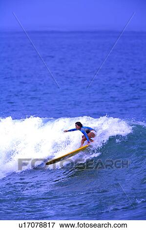 Stock Photo - Woman surfing through big wave skillfully. Fotosearch