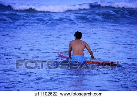 Young man standing in the sea and holding the surfboard View Large Photo Image Stock Image - Young man standing in the sea and holding the surfboard. Fotosearch
