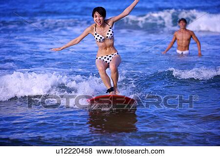 Young woman surfing on the sea and smiling happily View Large Photo Image Stock Photo - Young woman surfing on the sea and smiling happily. Fotosearch