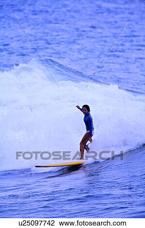 Young woman surfing on the sea skillfully with huge surf behind View Large Photo Image Stock Image - Young woman surfing on the sea skillfully with huge surf behind. Fotosearch