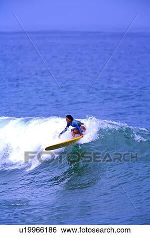 Stock Photograph - Young woman surfing on the sea skillfully. Fotosearch