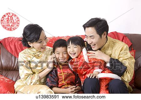 Stock Image - A family in traditional clothes sitting on the sofa and smiling happily. Fotosearch