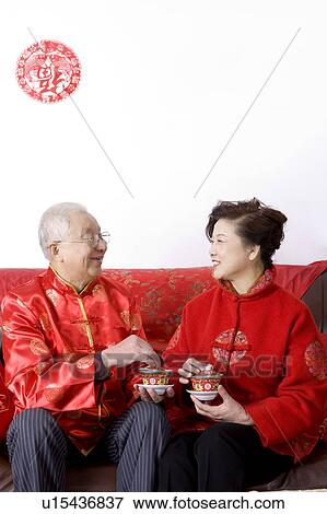 Stock Photo - Elderly couple in traditional clothes holding tea cup and smiling at each other. Fotosearch