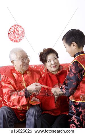 Stock Photography - Elderly couple in traditional clothes giving red envelope to little boy. Fotosearch