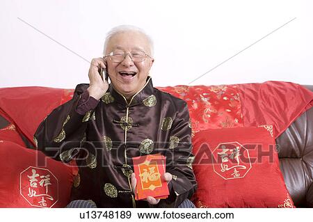 Elderly man in traditional clothes holding red envelopes and smiling happily, on the phone View Large Photo Image Stock Photo - Elderly man in traditional clothes holding red envelopes and smiling happily, on the phone. Fotosearch