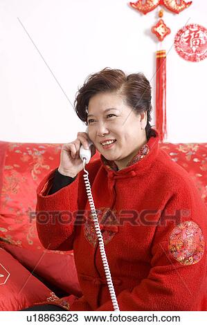 Stock Image - Elderly woman in traditional clothes smiling and on the phone. Fotosearch
