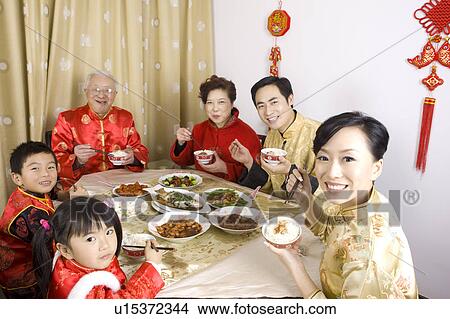 Family members in traditional clothes having dinner together and smiling at the camera View Large Photo Image Picture - Family members in traditional clothes having dinner together and smiling at the camera. Fotosearch