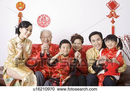 Stock Image - Family members in traditional clothes celebrating Chinese New Year. Fotosearch
