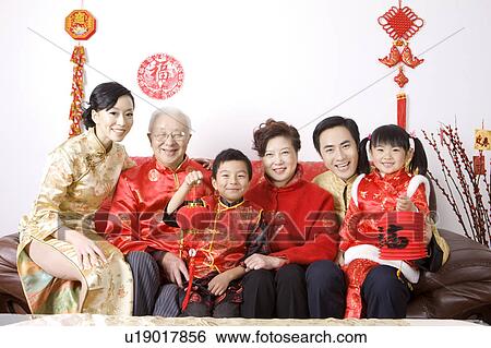 Stock Photograph - Family members in traditional clothes sitting on the sofa and smiling at the camera. Fotosearch