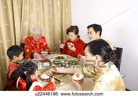 Family members in traditional clothes having dinner together View Large Photo Image Stock Photograph - Family members in traditional clothes having dinner together. Fotosearch