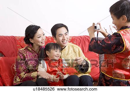 Stock Photograph - Little boy taking picture of young parents and little girl, smiling happily. Fotosearch