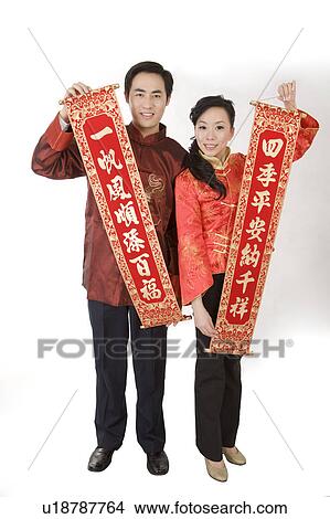 Young couple in traditional clothes holding the couplets and smiling at the camera View Large Photo Image Picture - Young couple in traditional clothes holding the couplets and smiling at the camera. Fotosearch