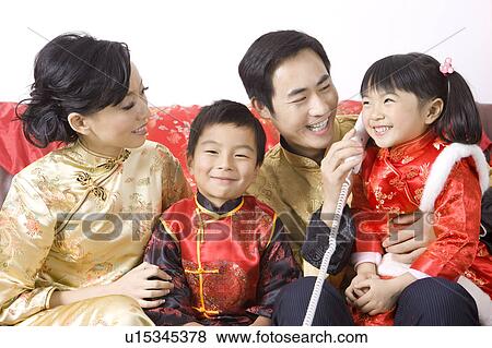 Stock Photo - Young family in traditional clothes smiling happily, on the phone. Fotosearch