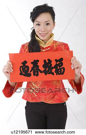 Stock Image - Young woman in traditional clothes holding the couplet and smiling at the camera. Fotosearch