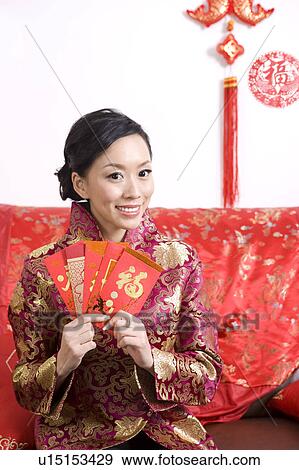 Young woman in traditional clothes showing red envelopes and smiling View Large Photo Image Stock Photo - Young woman in traditional clothes showing red envelopes and smiling. Fotosearch
