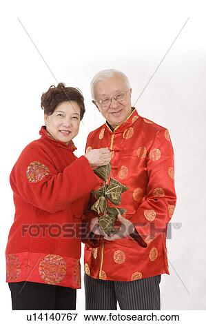 Elderly couple in traditional clothes holding Chinese rice dumplings and smiling at the camera View Large Photo Image Stock Photo - Elderly couple in traditional clothes holding Chinese rice dumplings and smiling at the camera. Fotosearch