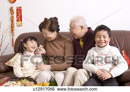 Elderly couple with two children sitting on the sofa and smiling happily View Large Photo Image Stock Photograph - Elderly couple with two children sitting on the sofa and smiling happily. Fotosearch