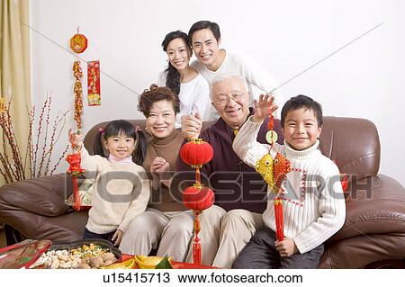 Stock Image - Family members holding Chinese New Year Ornaments and smiling at the camera. Fotosearch