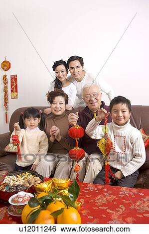Family members holding decorations and smiling at the camera View Large Photo Image Stock Photograph - Family members holding decorations and smiling at the camera. Fotosearch