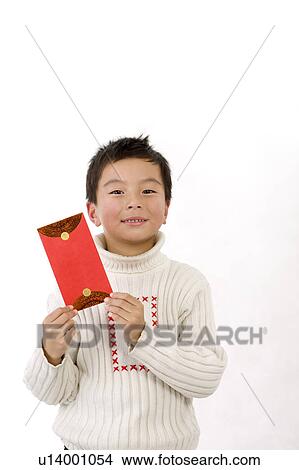 Picture - Little boy holding red envelope and looking at the camera. Fotosearch
