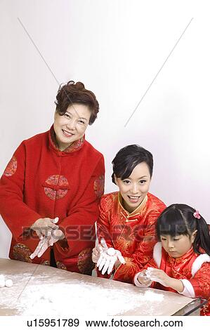 Two women and a little girl in traditional clothing making dumplings together View Large Photo Image Stock Photo - Two women and a little girl in traditional clothing making dumplings together. Fotosearch