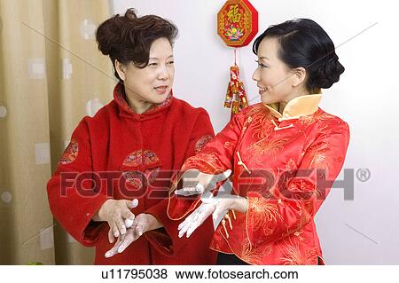 Stock Photo - Two women in traditional clothes making dumplings together. Fotosearch