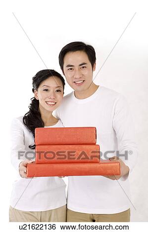 Stock Photograph - Young couple holding gifts and smiling at the camera. Fotosearch