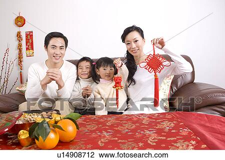 Stock Image - Young couple with two children holding Chinese decoration and looking at the camera. Fotosearch