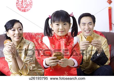 Stock Photography - Young family with one child holding moon cakes and smiling happily. Fotosearch