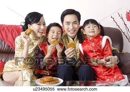 Stock Photography - Young family with two children in traditional clothing holding moon cakes and smiling at the camera. Fotosearch