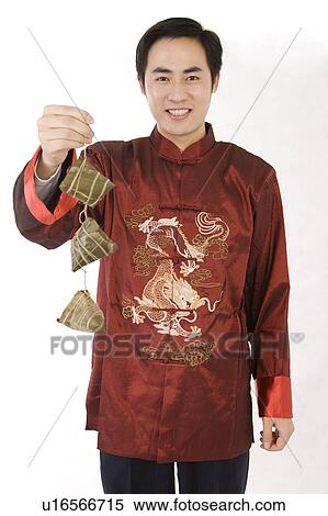 Young man in traditional clothes holding Chinese rice dumplings and smiling at the camera View Large Photo Image Stock Photography - Young man in traditional clothes holding Chinese rice dumplings and smiling at the camera. Fotosearch