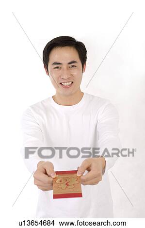 Picture - Young man showing a red envelope and smiling at the camera. Fotosearch