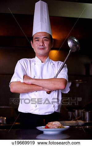 Stock Photo - Chef holding a cooking ladle with arms crossed and looking at the camera. Fotosearch