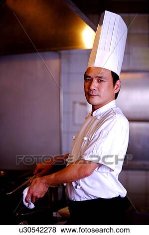 Stock Photo - Chef holding the pan and spatula, looking at the camera. Fotosearch