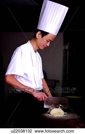 Stock Image - Chef preparing food before a cutting board. Fotosearch