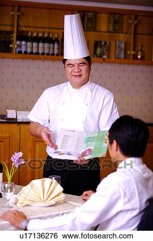 Chef showing the menu to the customer and smiling View Large Photo Image Stock Photograph - Chef showing the menu to the customer and smiling. Fotosearch