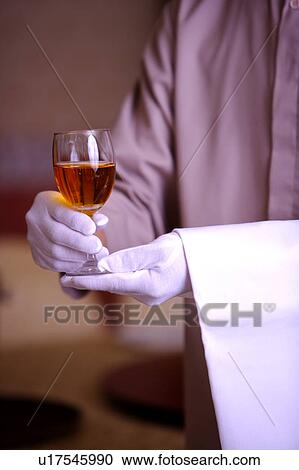 Stock Image - Close-up of hands holding a wine glass of drink. Fotosearch