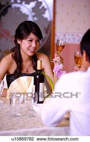 Man and woman sitting near the table and holding a glass of wine View Large Photo Image Stock Image - Man and woman sitting near the table and holding a glass of wine. Fotosearch