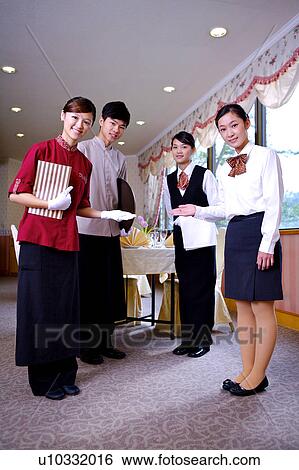 Stock Photograph - Three waitresses and a waiter gesturing and looking at the camera. Fotosearch