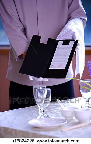 Waiter standing near the table and showing the bill View Large Photo Image Stock Photograph - Waiter standing near the table and showing the bill. Fotosearch