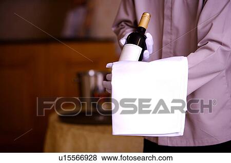 Young waiter holding a bottle of red wine View Large Photo Image Stock Photo - Young waiter holding a bottle of red wine. Fotosearch